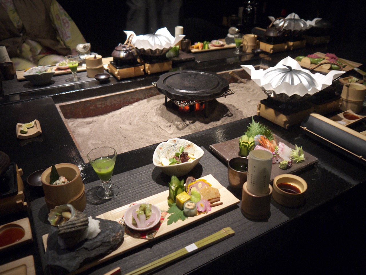 Japanese ryokan Fancy dinner served on the table with various gourmet kaiseki meals, traditional irori fireplace with glowing coals Japanese kaiseki dinner with sushi, sashimi, and hot plate cooking at a ryokan table
